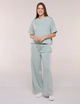 Conjunto de buzo de manga corta con hombros caídos y escote redondo, acompañado de un pantalón tipo wide leg de tiro alto con cintura elástica y cordón de ajuste, en color verde.