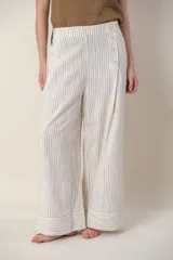 Pantalón ancho de lino color crudo con rayas verticales en tonos celeste, naranja y rosa. Tiene bolsillos laterales y cierre con botones a la vista en el lateral.