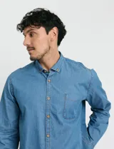 Camisa de jean de manga larga con cuello clásico, cierre frontal con botones y bolsillo tipo parche en el pecho.