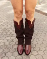 Bota de caña alta marca Austera confeccionada artesanalmente en cuero y gamuza color chocolate. Presenta un diseño versátil tipo polaina desmontable sobre bota corta de cuero liso.
