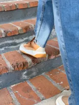 Zapatillas deportivas de cuero color camel con cordones marrones y suela blanca.