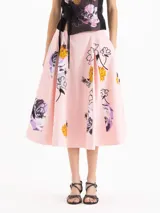 Pollera midi evasé tableada de color rosado, confeccionada en algodón con un estampado de flores y abejas, enriquecido con bordado de mostacillas.