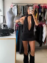 Vestido corto negro con diseño de cuello halter, escote profundo y espalda descubierta, confeccionado en tela liviana con caída.