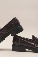 Mocasín Helen de cuero vacuno con acabado charol, color negro. Cuenta con un taco de 3,5 cm y suela de goma.