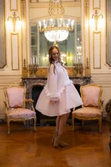 Vestido corto de lino en color rosa claro, con diseño holgado, mangas largas abullonadas con volados en contraste y cierre frontal con botones forrados.