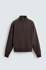 Jersey de punto de corte regular, color gris oscuro, con cuello subido y cierre frontal de cremallera. Presenta mangas largas y acabados en rib en puños y ruedo.