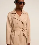 Buzo femenino modelo trench coat, confeccionado en poliéster con detalles acetinados. Posee cuello solapa, cierre delantero con 6 botones matizados y lazo con faixa pespontada.
