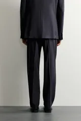 Pantalón de traje relaxed fit color negro, confeccionado en tejido con lana, con bolsillos frontales, bolsillos traseros de doble vivo con botón y raya marcada en las piernas.