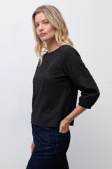 Remera blanca de manga tres cuartos con detalles de bordado calado en el frente y en los hombros, con cuello redondo y puños elásticos.
