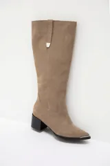 Bota bucanera de cuero color marrón oscuro, con taco cuadrado de 6 cm y punta fina con detalle metálico. Presenta una tira vertical decorativa con tachas metálicas en la parte superior de la caña.