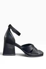 Sandalia de cuero negro, modelo Tango, con taco ancho, plataforma delantera, tiras cruzadas en el empeine y tira ajustable con hebilla al tobillo.
