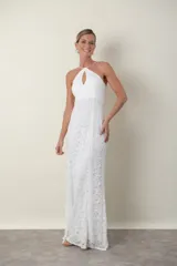 Vestido largo de encaje blanco, con breteles finos cruzados en la espalda y escote halter con abertura en forma de gota.