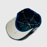 Gorra tipo baseball de pana color azul, con bordado frontal en tipografía gótica y bordado lateral de una paloma. Cuenta con ajuste posterior.