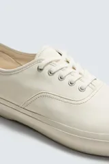 Zapatilla de cordones color blanco hueso, con capellada lisa de piel y suela de goma a tono.