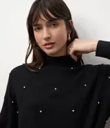 Suéter de punto color negro con cuello medio estructurado y mangas largas. Presenta un patrón geométrico sutil y aplicación de beads distribuidos por toda la parte frontal.