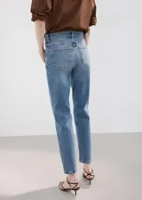 Jeans de denim azul con tiro medio, corte recto y largo al tobillo.