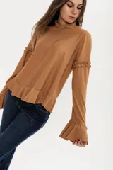 Remera color camel de algodón peletizado, corte amplio, cuello alto y mangas largas con volados en los hombros y puños.