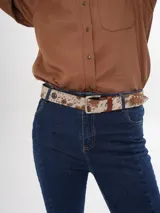 Cinturón de cuero con estampado animal, hebilla metálica rectangular y apliques metálicos decorativos.