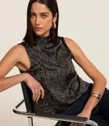 Blusa sin mangas de poliéster satinado color negro con estampado geométrico de líneas blancas y cuello alto drapeado.