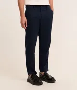 Pantalón de vestir azul marino, de corte relajado, confeccionado en tejido de viscosa y lino. Cuenta con cintura con trabillas, bolsillos laterales y traseros. Se ajusta a la cintura con cinturón de cuero marrón.