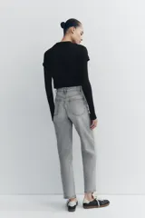 Jeans de tiro alto color negro con efecto lavado, corte mom fit, cinco bolsillos y cierre frontal con cremallera y botón metálico.