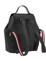 Mochila negra de poliuretano con forro de poliéster. Presenta un diseño estructurado con solapa superior que cierra con broche magnético y un asa de mano superior. En el centro de la solapa lleva un monograma metálico TH.