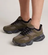 Championes estilo dad sneaker de hombre, color verde militar, con recortes en tonos oscuros, cordones negros y suela gruesa texturizada.