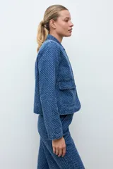 Chaqueta de jean azul con textura de efecto desgastado, cuello clásico y cierre frontal.