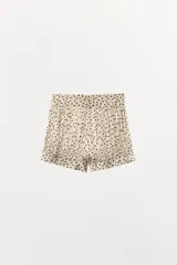 Shorts de tiro medio con estampado de lunares, confeccionado en viscosa. Presenta diseño con pliegues, bajo abullonado con puño y botones, y cierre frontal con botones forrados.
