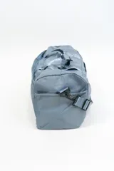 Bolso de viaje gris con doble asa corta y cierre superior. Estampado frontal con la frase "The Tote Bag" en letras blancas.