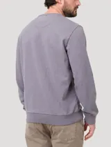 Buzo de algodón orgánico color gris jaspeado, con cuello redondo y terminaciones en rib en cuello, puños y pretina. Presenta un pequeño parche bordado de un pato en el pecho.