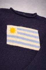 Sweater de tejido de punto en color azul marino, con diseño de la bandera de Uruguay tejida en el frente. Presenta cuello redondo, mangas largas y un corte holgado.
