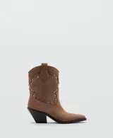 Botines de estilo texano en color marrón claro, confeccionados en piel bovina, con diseño de caña baja, puntera fina y detalles de tachas metálicas en la parte frontal y lateral.