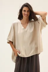 Blusa beige de seda con escote en V y mangas cortas tipo murciélago.