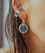 Aros colgantes dorados con dije circular de resina color turquesa, bordeado con strass. El arito es de acero quirúrgico.