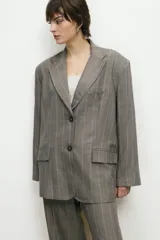 Blazer sastrero gris con rayas verticales rosadas, corte oversize, solapas con muesca, cierre con dos botones y bolsillos con solapa.