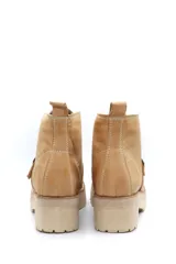 Borcego de cuero color beige con cordones, suela track de goma y detalle de hebilla metálica en el empeine.
