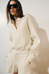 Jersey de punto waffle de algodón color beige, con cuello redondo, cierre frontal parcial con botones en contraste y manga larga con puños elásticos.