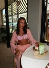 Conjunto de bikini estampado con flores y hojas en tonos rosados, amarillos y verdes. Incluye corpiño con aro y bombacha con lazos laterales.