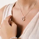 Conjunto de collar y dije en plata 925, compuesto por una cadena fina y un dije circular con diseño orgánico entrelazado.