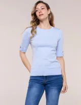 Buzo confeccionado en tejido de punto color beige, de silueta semi entallada, con escote redondo, mangas al codo con detalles metálicos en los puños y terminaciones acanaladas.