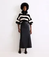 Falda midi negra de cuero sintético, corte recto, con abertura trasera y cintura alta.