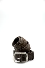 Cinturón de cuero con pelo en tono oscuro, con hebilla metálica plateada de diseño rectangular.