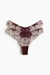 Pack de dos bombachas tipo brazilian de tiro bajo, confeccionadas en malla bordó con encaje floral en tonos beige y bordó. Presentan cintura en V y detalle de pequeños moños decorativos en la parte frontal.