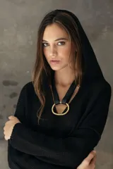 Gargantilla de cuero marrón con un dije central en forma de círculo irregular de bronce pulido.