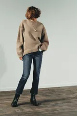 Jeans de tiro alto color marrón oscuro con acabado lavado, corte recto/flare y bajo cropped sin costuras. Presenta cinco bolsillos y cierre frontal con cremallera y botón metálico.