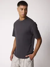 Remera básica gris oscuro con cuello redondo y mangas cortas, de corte relajado.