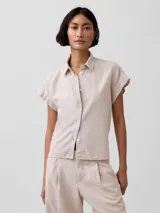 Camisa de lino color off white, de manga corta con vuelta, cuello camisero clásico y cierre frontal de botones.