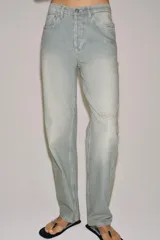Jeans de tiro bajo y corte recto, confeccionados en denim con estampado de rayas verticales y efecto lavado. Presenta cinco bolsillos, trabillas en la cintura, cierre frontal con cremallera y botón, y un detalle de rotura en la parte delantera.