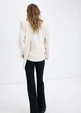 Blazer Martin de diseño recto y color beige, con cuello en pico, sin solapa, manga larga y bolsillos frontales de parche. Incluye forro interior.